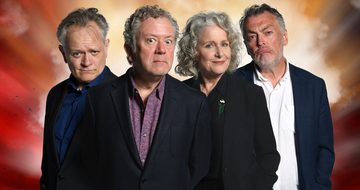 Jon Culshaw, Jan Ravens, Lewis MacLeod, and Duncan Wisbey all stand together wearing suits and staring at the camera in a thoughtful manner