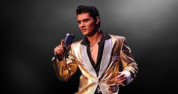 Emilio in a black shirt and gold blazer, with his black hair quaffed like Elvis' holding a microphone
