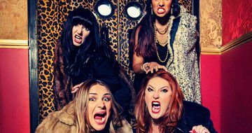 Four women in fur coats pretend to roar at the camera while stood in front of leopard print doors
