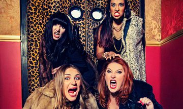 Four women in fur coats pretend to roar at the camera while stood in front of leopard print doors