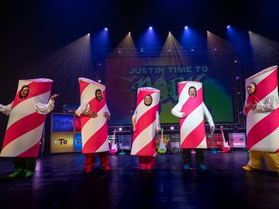 All the actors on stage smiling dressed as sticks of rock