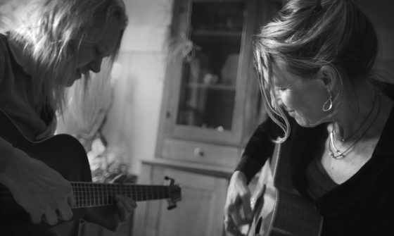 A black and white image of Jon (on the left) and Martha (on the right) facing each other and playing their guitars