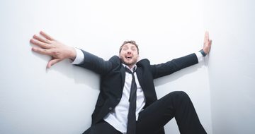 Wearing a suit and tie, Seann Walsh, a young comedian with messy brown hair, pushes at the big white walls which look to be closing in on him
