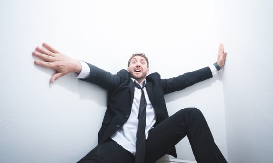 Wearing a suit and tie, Seann Walsh, a young comedian with messy brown hair, pushes at the big white walls which look to be closing in on him