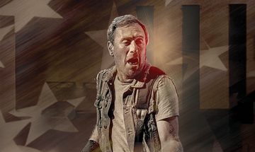 A Bruce Springsteen impersonator in a t-shirt and vest with his mouth open playing a guitar which is just out of shot