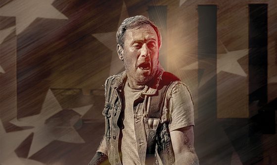 A Bruce Springsteen impersonator in a t-shirt and vest with his mouth open playing a guitar which is just out of shot