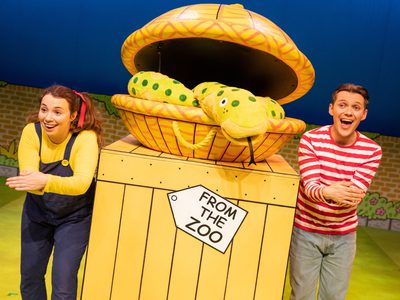 A man and woman next to a yellow crate with a label saying 'From The Zoo' between them. On top of the crate is a basket with a snake puppet coming out