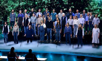 A large group of farmers all dressed in blue stood on the Britain's Got Talent stage with fog around their feet and foliage projected behind them
