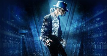 A performer dressed as Michael Jackson in a white top, black trousers and sparkly jacket, with a silver glove and black hat