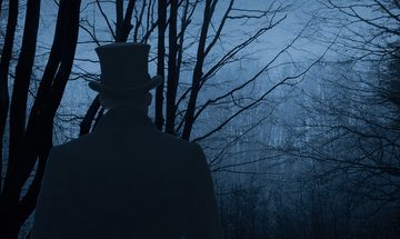 An eery image of a man's silhouette wearing a top hat and jacket, standing outdoors among bare trees.