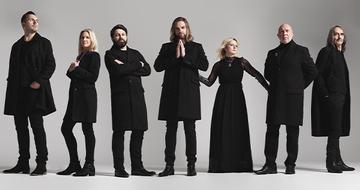Rumours of Fleetwood Mac stood in a line wearing all-black outfits on a grey background