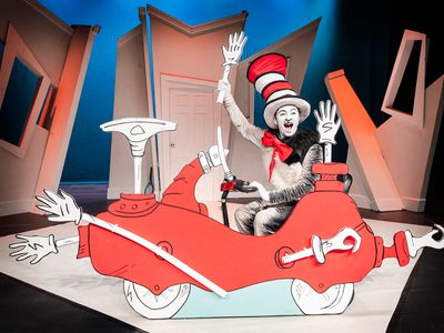 The Cat in the Hat rides a cardboard vehicle