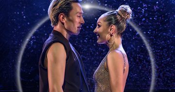 Carlos wears his hair slicked back and a black sleeveless vest. Amy faces him wearing a sparkly dress and her hair in a high bun.