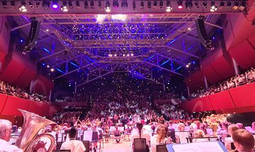 A photo from the back of The Anvil stage looking over lots of students playing instruments, dancing, and having confetti fall from the ceiling