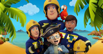 Fireman Sam in his navy blue uniform and yellow helmet crosses his arms while a parrot sits on his shoulder. In front of him are two other firefighters and a small red haired boy in a blue jacket, glasses and a pirate hat. They all stand on a beach.