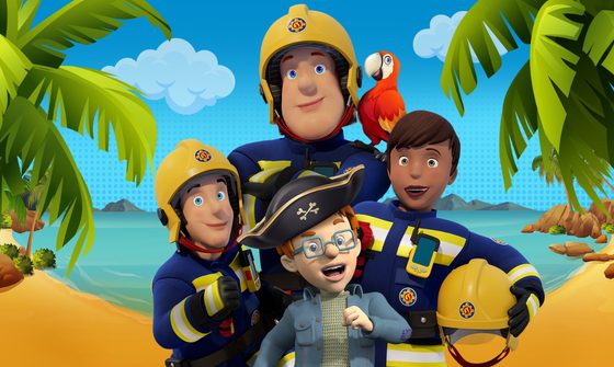 Fireman Sam in his navy blue uniform and yellow helmet crosses his arms while a parrot sits on his shoulder. In front of him are two other firefighters and a small red haired boy in a blue jacket, glasses and a pirate hat. They all stand on a beach.