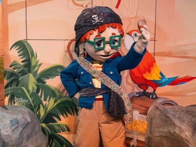 Fireman Sam's friend dressed as a pirate standing next to a parrot.