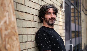 Mark Watson leaning against a brick wall