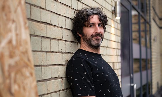 Mark Watson leaning against a brick wall