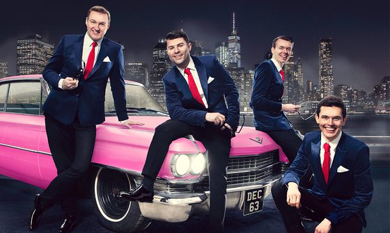 Four men in blue suits with red ties sat on and around of a pink Cadillac with a city scape behind