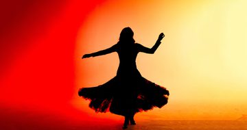 a silhouette of a dancer in a pleated skirt against a red and orange background