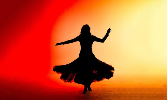 a silhouette of a dancer in a pleated skirt against a red and orange background