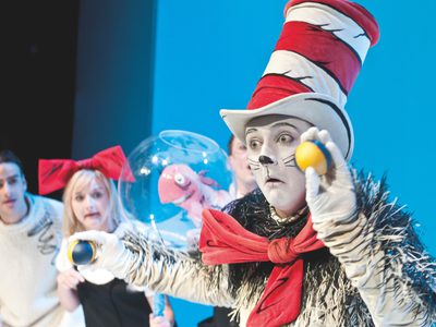 The Cat in the Hat, looks as if he's about to throw a ball. Sally, her brother, and the fish look on waiting to see what he'll do