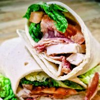 a chicken caesar wrap on a wooden board