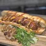 a hot dog with mustard, ketchup and mushrooms and salad on the side